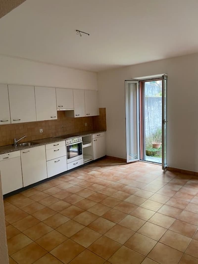 Kitchen with tiled flooring, white cabinets, stainless steel appliances, sink, glass door to a small outdoor space, natural light