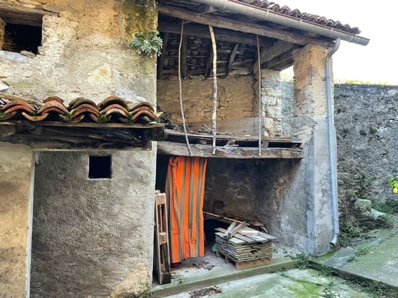 stone house, raised ground floor, wooden door, wooden planks, pile of tiles