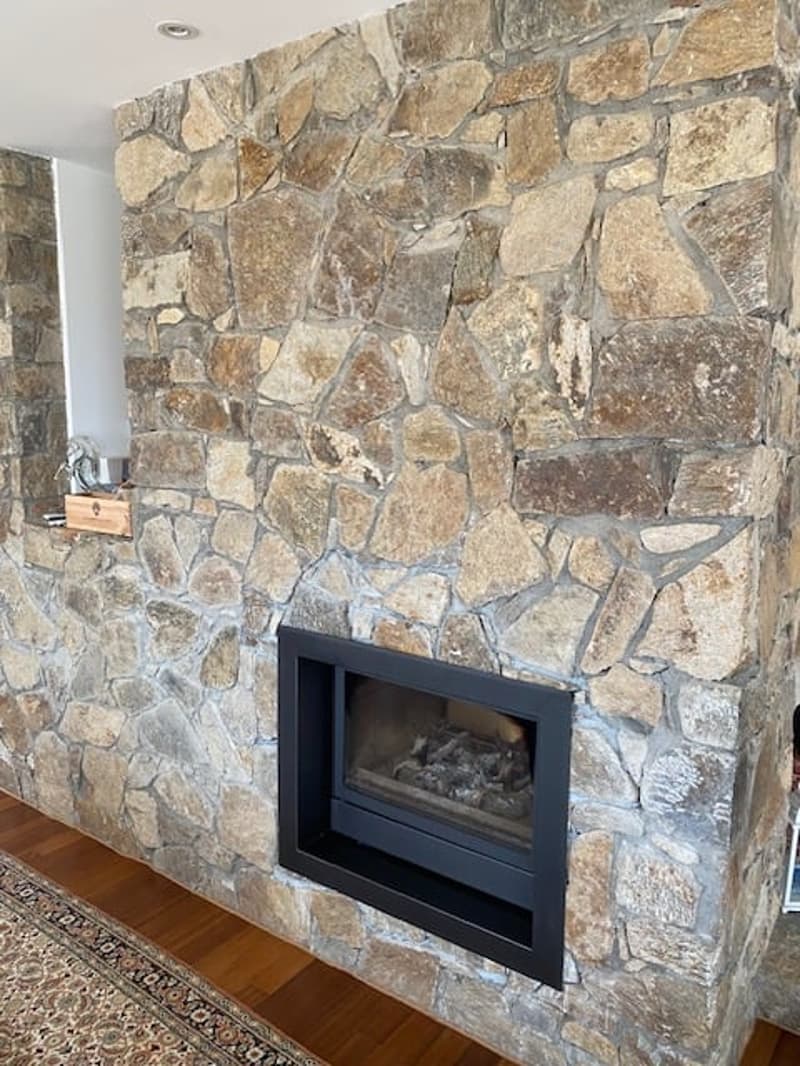 Stone fireplace, black fireplace, wooden floor, rug