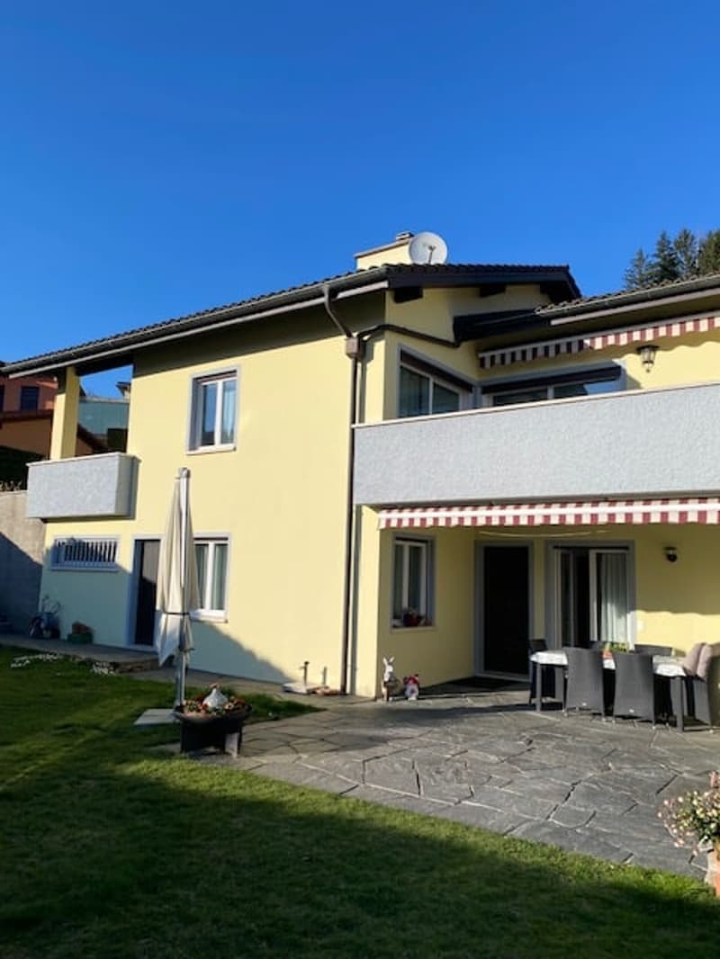 2 story house, yellow exterior, balcony, patio with table and chairs, garden, satellite dish