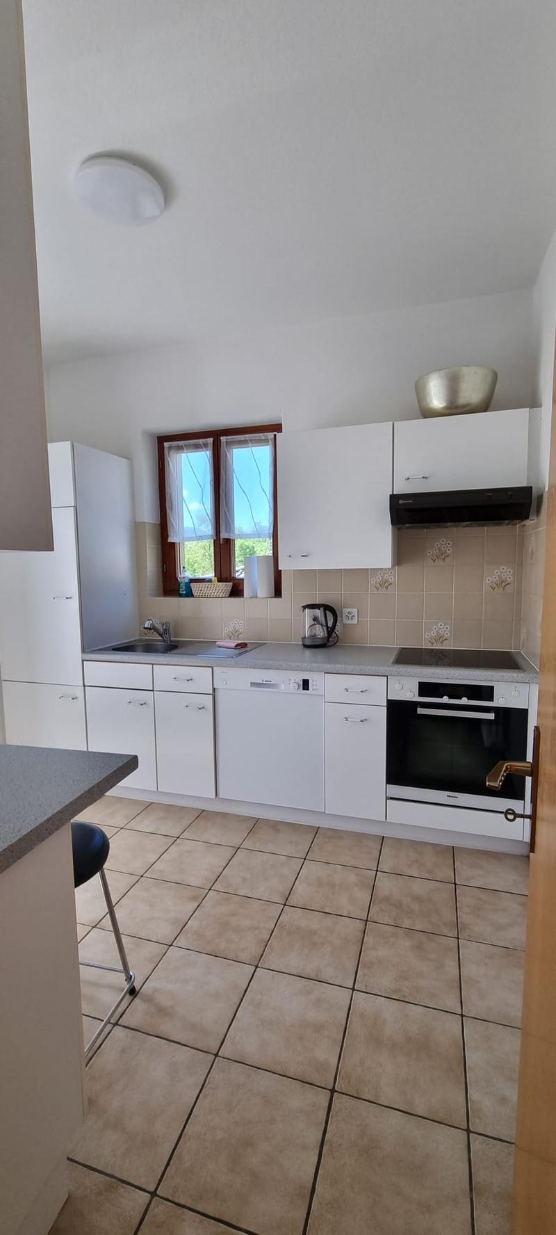 modern kitchen with white cabinets, tiled floor, dishwasher, washing machine, gas stove, oven, sink, faucet, window, ceiling lamp