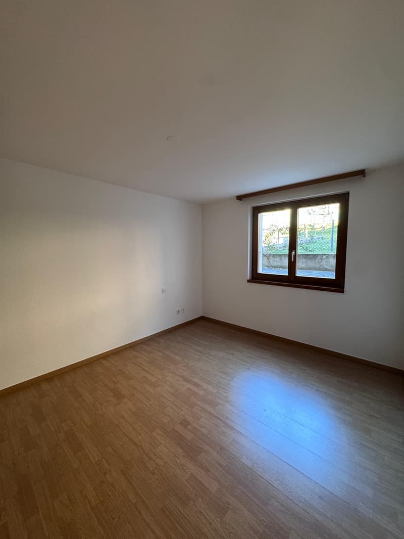 empty room with wooden floors, white walls, window with view