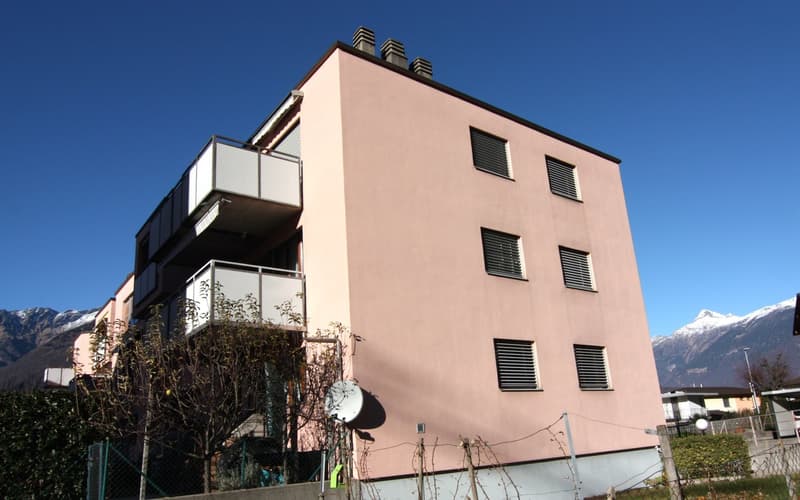 Apartment building, pink facade, 5 floors, balconies on each floor, mountains in the background