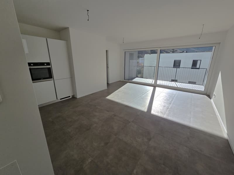 Modern kitchen, empty room, white walls, tiled flooring, sliding glass door to balcony, sunlight shining through