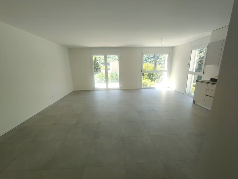 Spacious open-plan living area with large windows, light-colored tile flooring, and a minimalist, modern design.