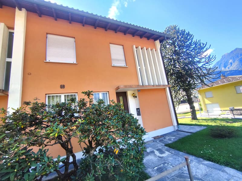 2-story orange building with white windows, balcony, surrounded by lush greenery and a tree with distinctive branches
