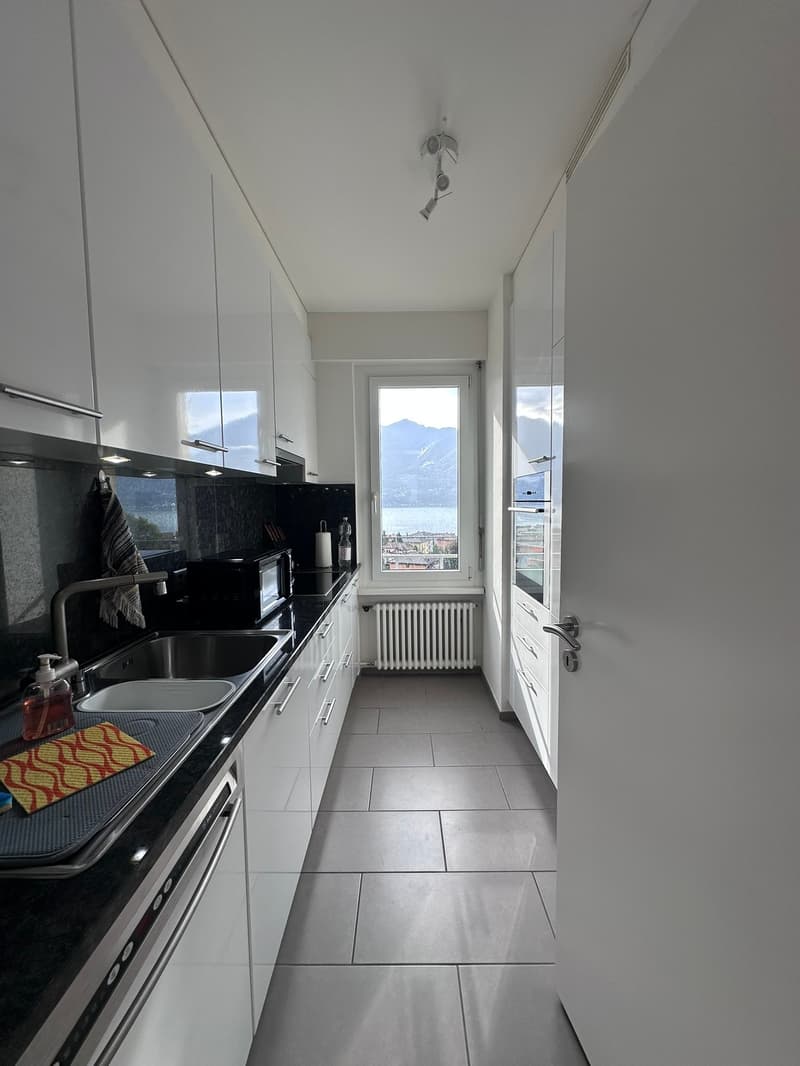 modern kitchen with large window overlooking the mountains and a view of the lake