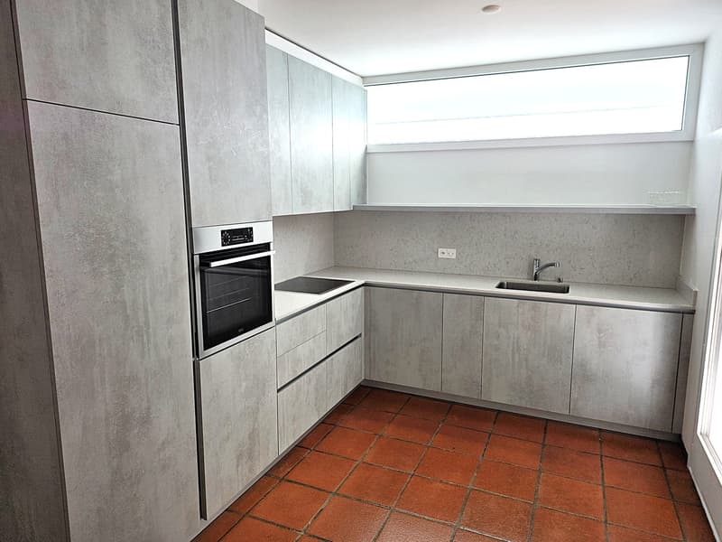 modern kitchen with gray cabinets, red tiled floor, built-in oven, sink, faucet, window