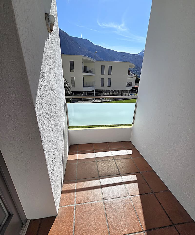 Balcony with tiled floor, glass railing, wall lamp, view of mountains