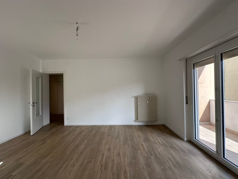 empty room, wooden floor, white walls, sliding glass door, balcony, radiator, open door