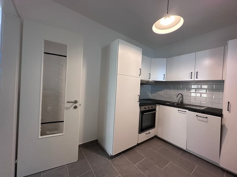 modern kitchen with white cabinets, black countertops, built-in oven, sink, faucet, dishwasher, washing machine