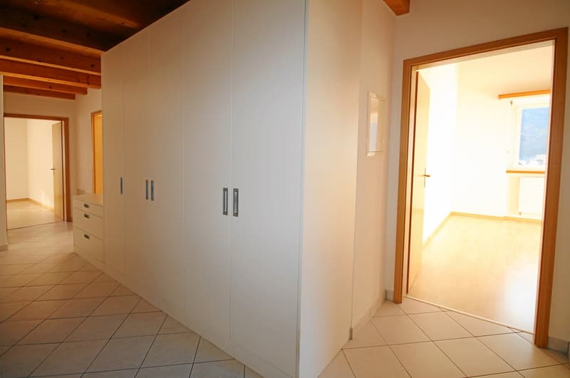 empty room with built-in closets, white tiles on the floor, two doors, wooden beams on the ceiling