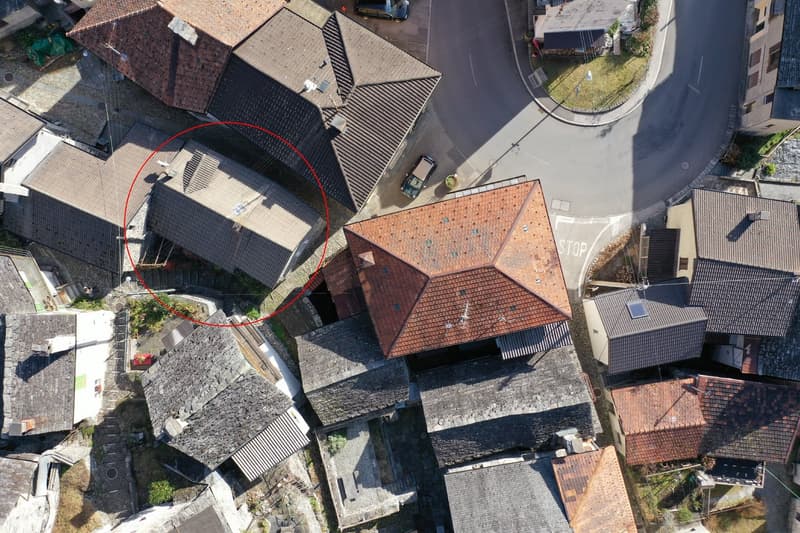 Aerial view of a residential area with a two-story house with a balcony or terrace visible in the circled area.
