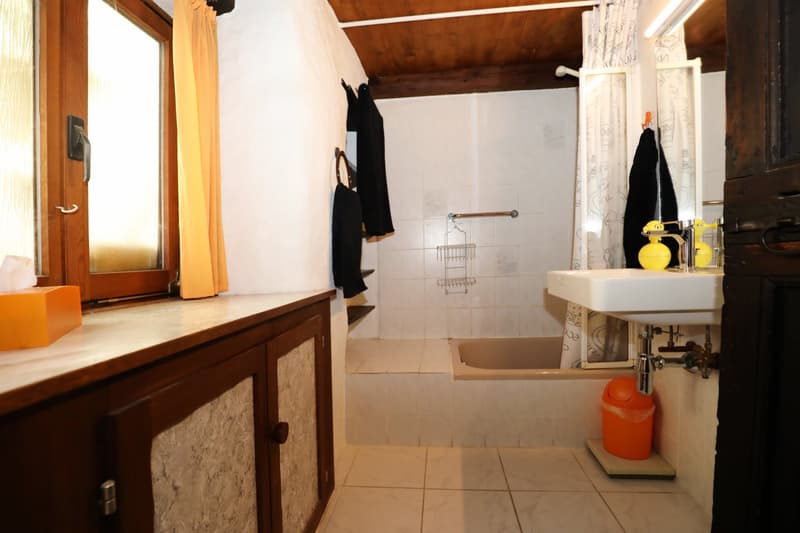 Bathroom with wooden ceiling, white walls, tiled floor, vanity with sink, shower curtain, and a private washing machine