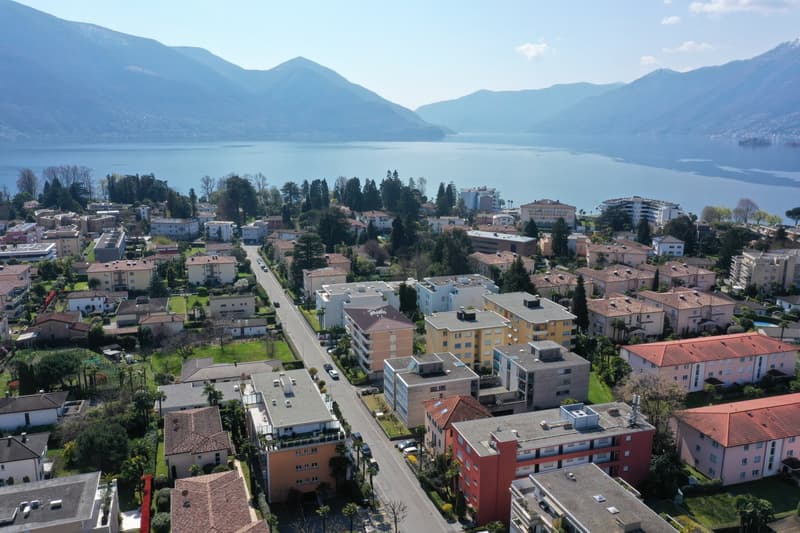 Aerial view of a town with many buildings, a road, and a lake in the background.