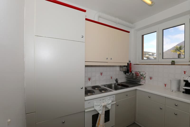 modern kitchen with white cabinets, gas stove, sink, dishwasher, white countertops, windows