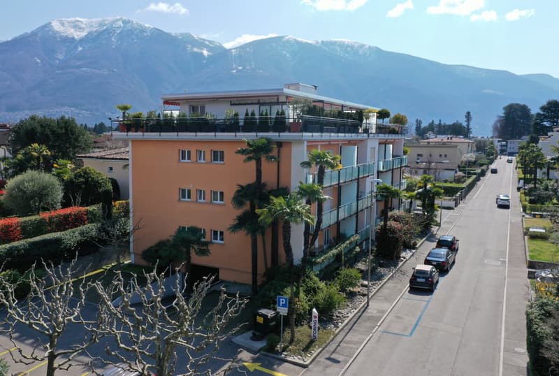 3 story building, orange exterior, multiple balconies, parking area, mountain view