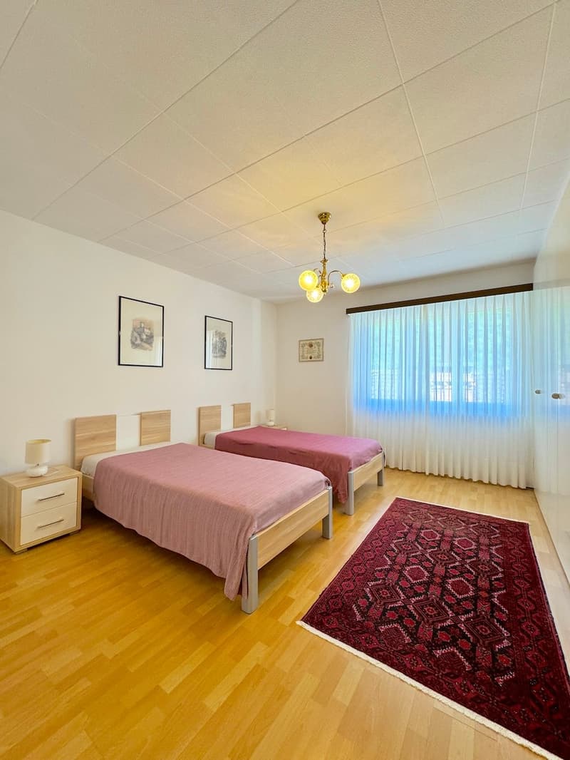 Two single beds, nightstands, lamp, framed art on the wall, carpet, chandelier