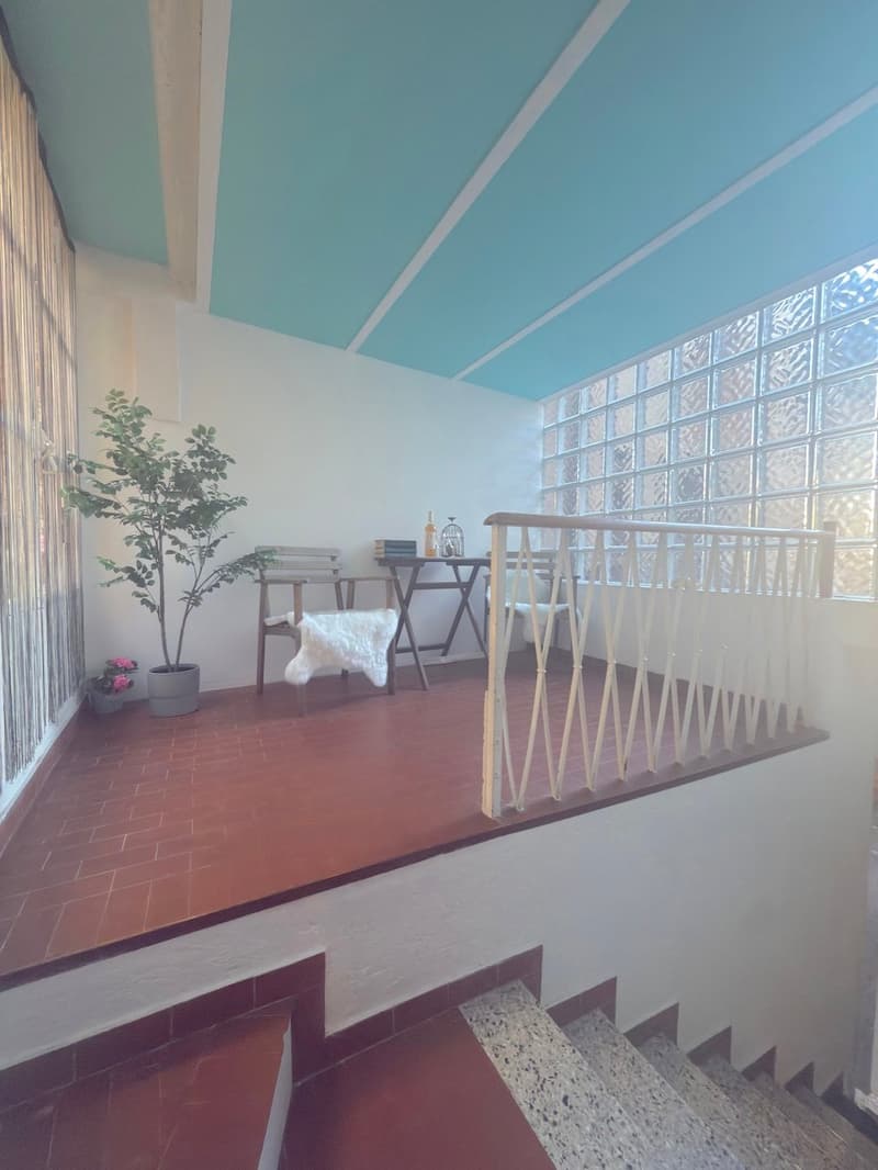Balcony/terrace with tiled floor, two chairs, table, potted plants, and a blue ceiling.
