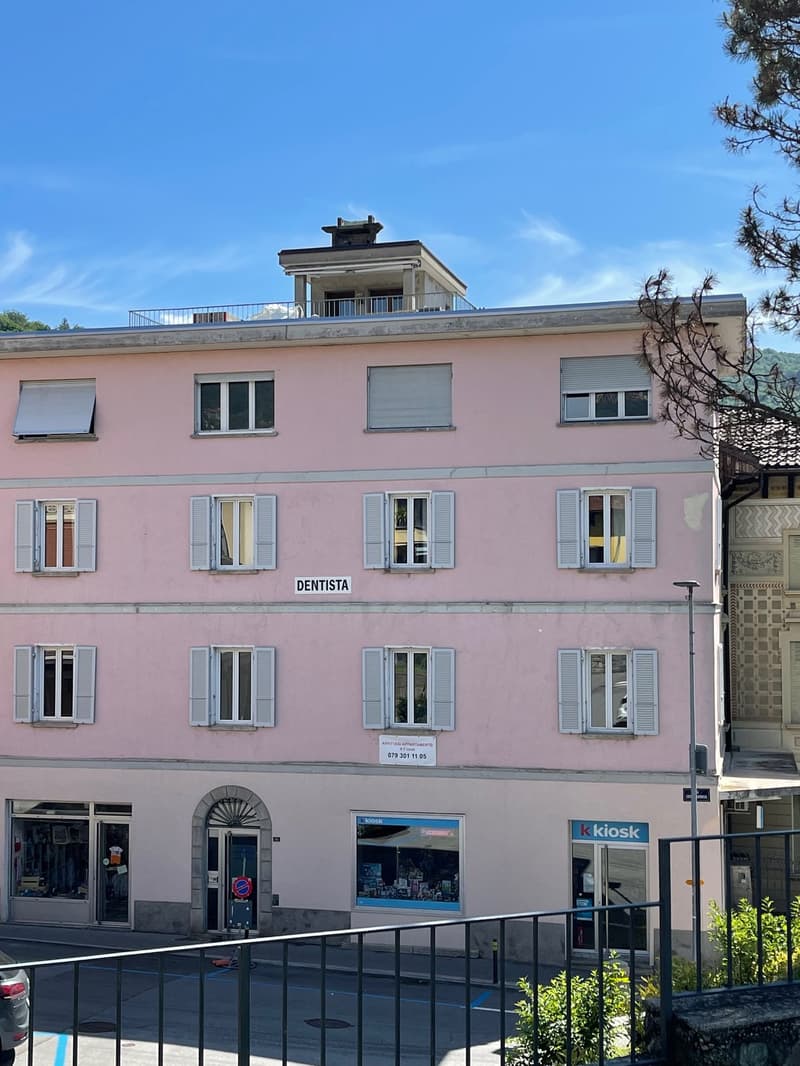 Pink building with several windows and shutters, Dentista sign above one of the entrances, sign for Kiosk store at ground level