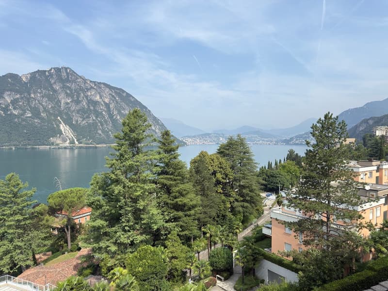 Beautiful view of a lake, surrounded by mountains, trees, and buildings