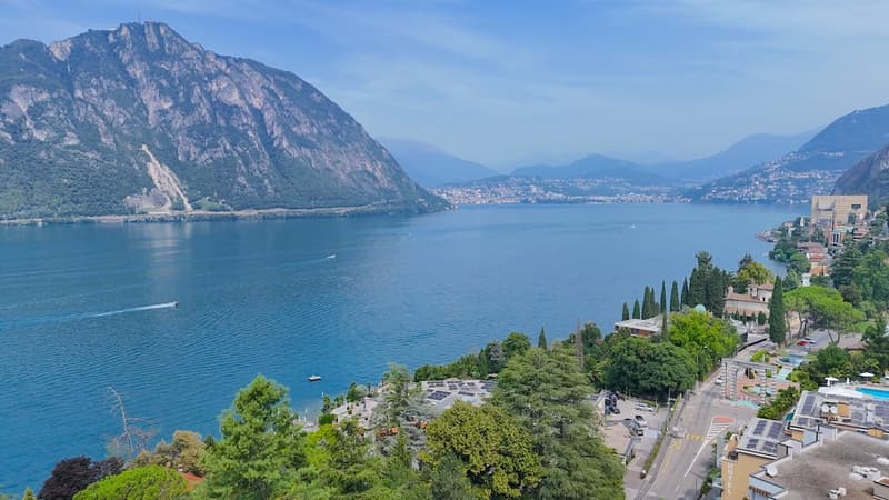 An aerial view of a lake surrounded by mountains with some boats on the lake