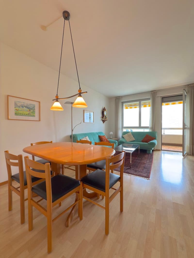 wooden dining table with 6 chairs, yellow lamp, 2 blue sofas, rug, coffee table, picture frame, white curtains