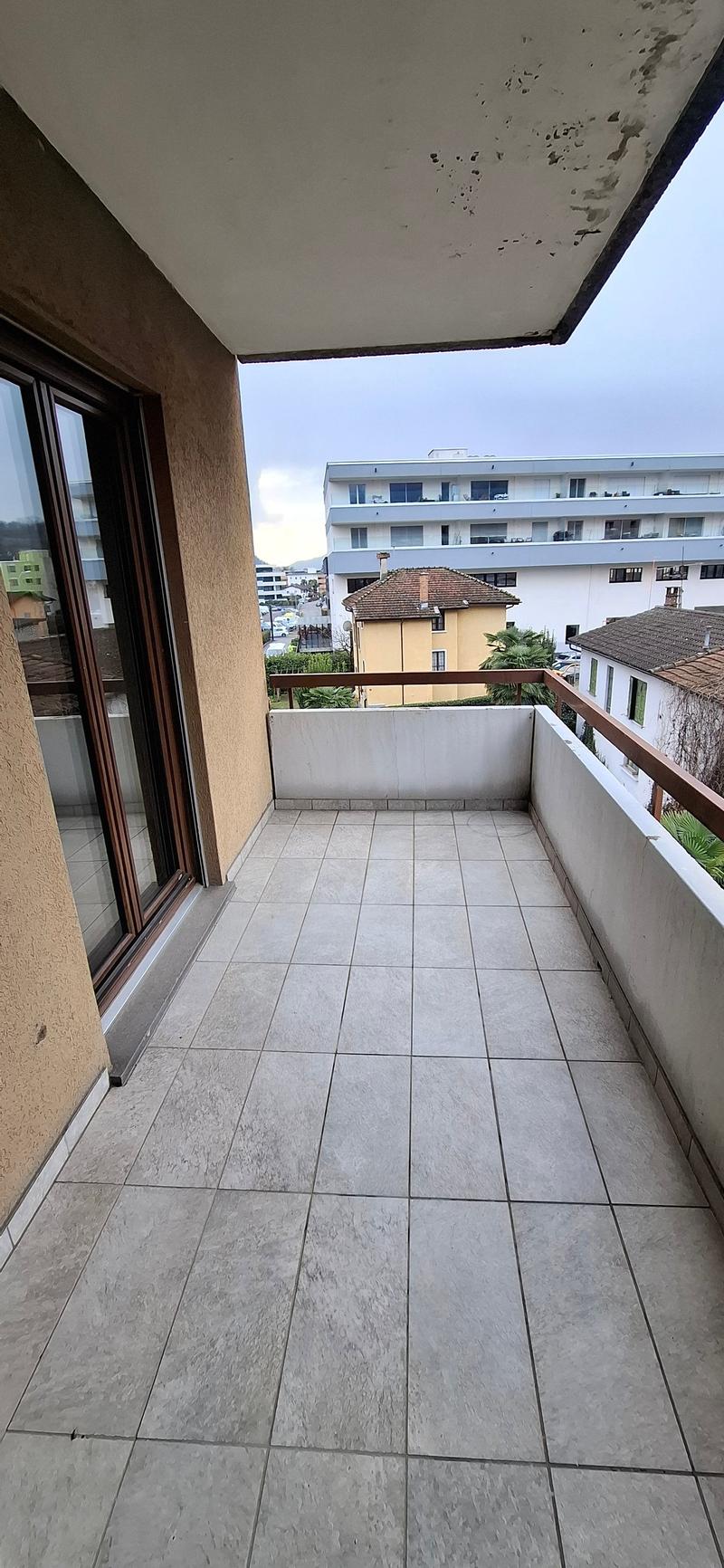 Balcony with tiled floor, brown railings, and an open view