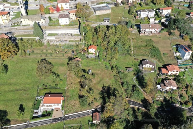 Aerial view of a rural neighborhood with several houses, greenery, and buildings.