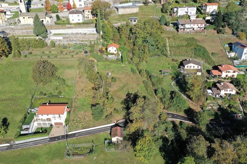 group of residential buildings in a rural area, with a clear view of the hills, a road in the middle of the image, green grass and trees