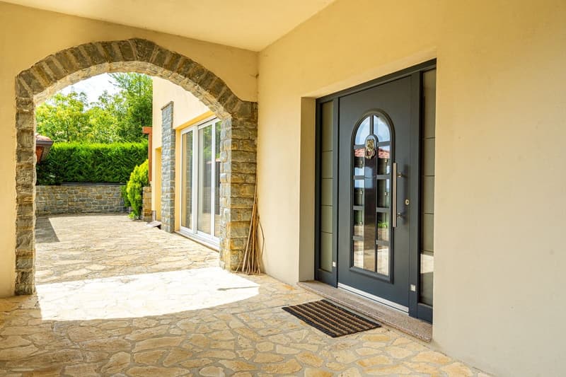 Stone archway entrance, stone wall, glass door, stone floor, mat in front of door