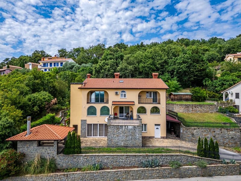 Two-story house with a terrace, surrounded by a stone wall, with a view of the surrounding area