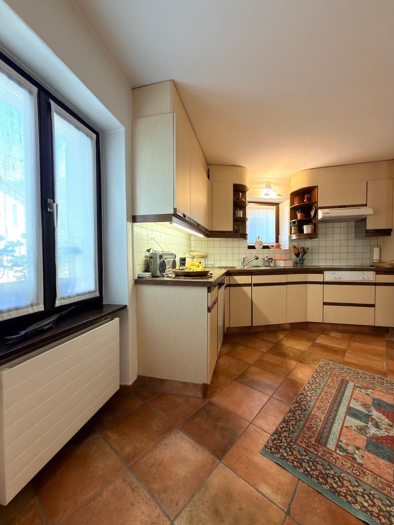 kitchen with wooden cabinets, tiled floor, sink, faucet, window, plate rack, radio, bowl, plate, towel, rug