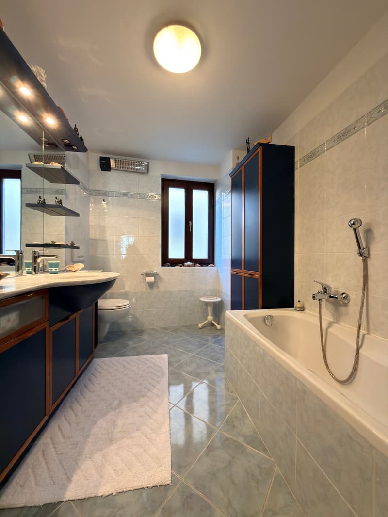 Bathroom with bathtub, sink, toilet, cabinet, and a window