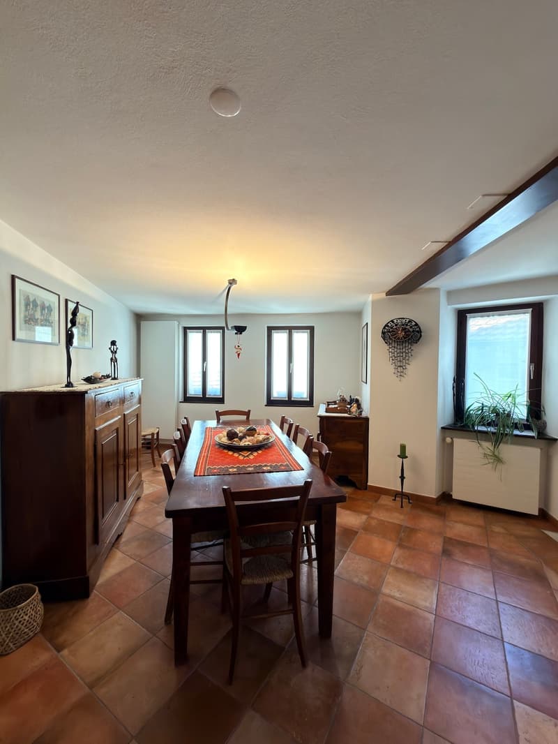 Dining room with wooden table, chairs, wooden cabinet, radiator, windows, picture frames, decorative items