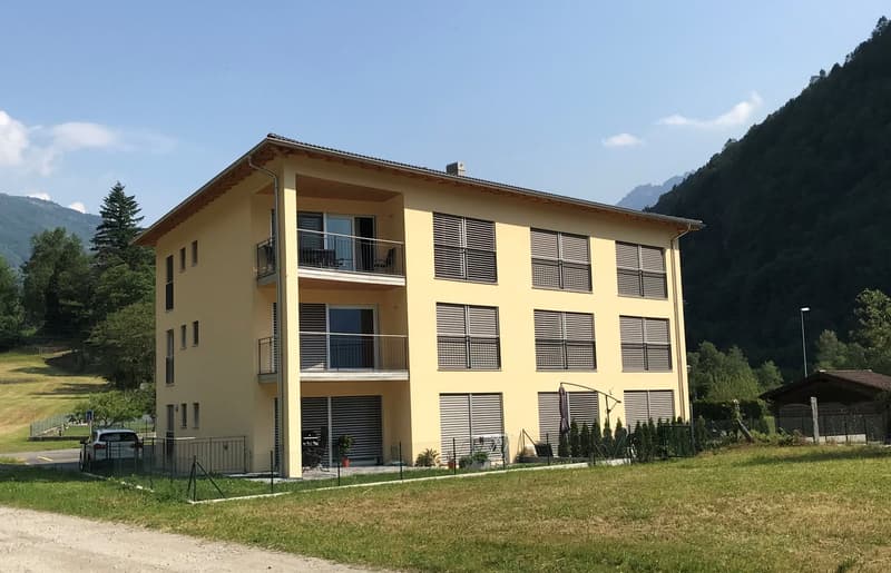 Yellow apartment building, multiple balconies, modern design, 2 floors, mountain view, car parked in front