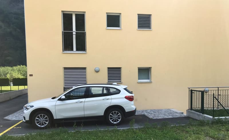 3-story building, yellow facade, 5 windows, white SUV parked in front, garage door on the right side