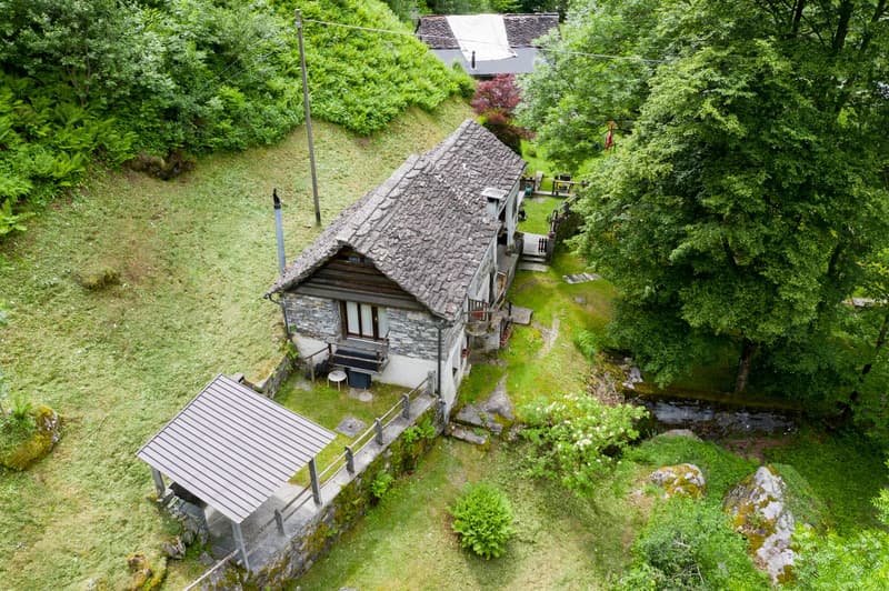 stone and wood exterior, steep surroundings, roof covered with rocks, fenced garden