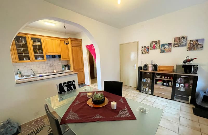 dining room, kitchen, glass table, chairs, potted plant, microwave, cabinet, sink, faucet, bottles, art