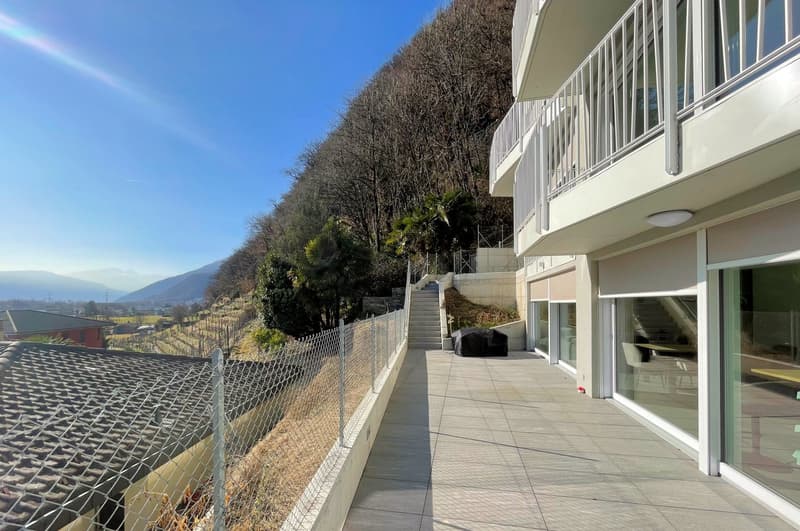 A two story house with a balcony, tiled pathway, chain link fence, and stairs leading to a staircase with handrails.