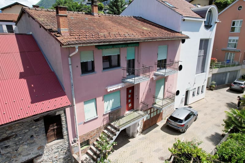 two story building, red roofs, windows with shutters, stairs leading to entrance, balconies, parked cars