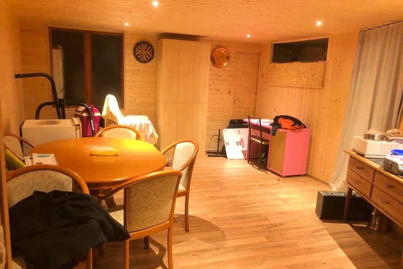 wooden flooring, round dining table with chairs, storage unit, small table with items, large wall mounted mirror, small window, small desk with items