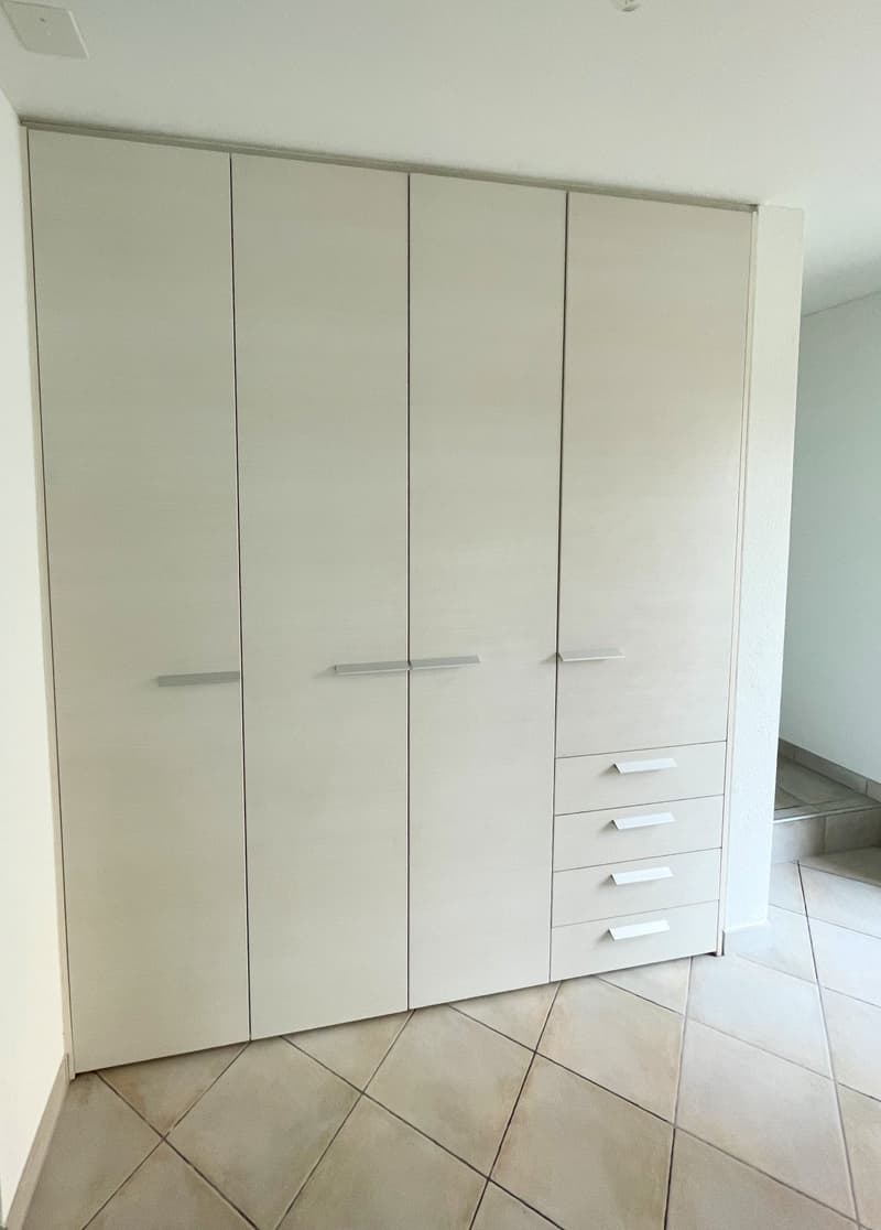 white built-in wardrobe with hanging rods, 3 doors with drawers, tile flooring