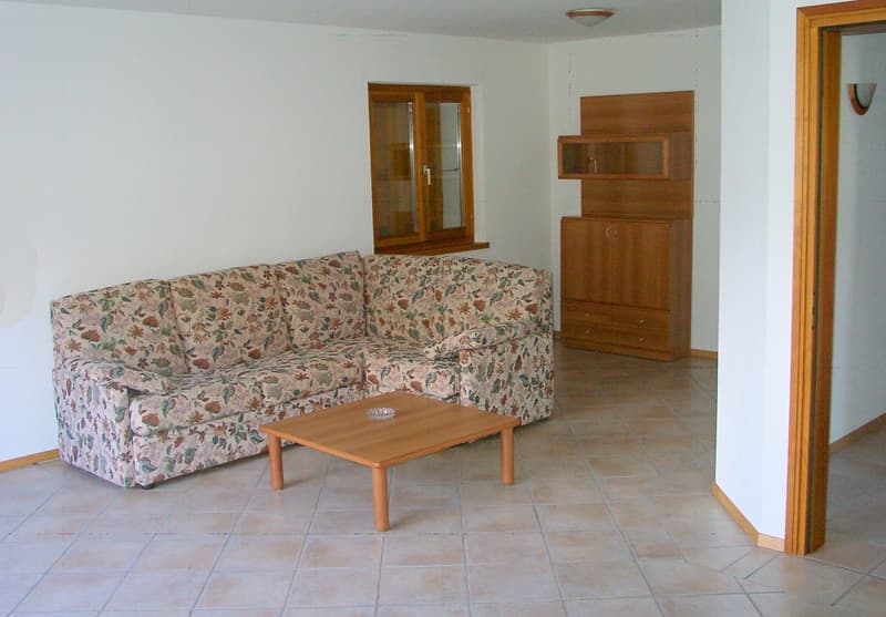 floral print couch, wooden table, wall mounted lamp, cupboard, window