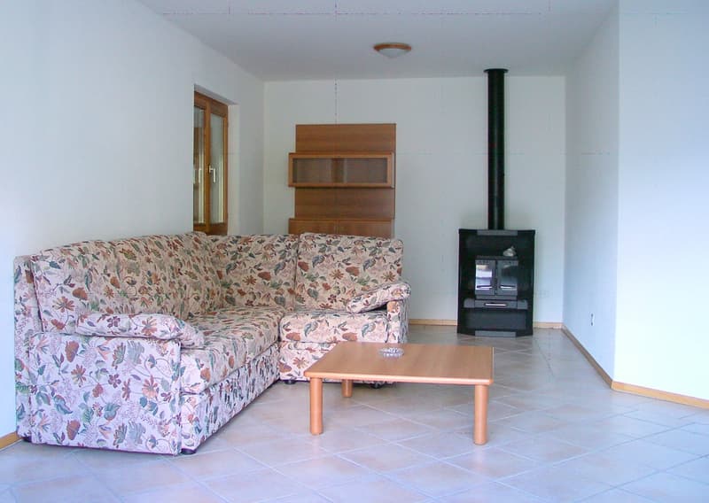 U-shaped floral couch, wooden coffee table, fireplace, wooden shelves, sliding glass door