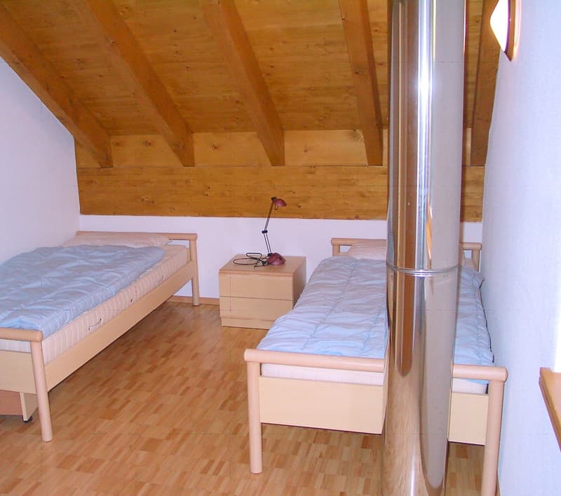 2 beds, nightstand, red lamp, wood flooring, wooden ceiling