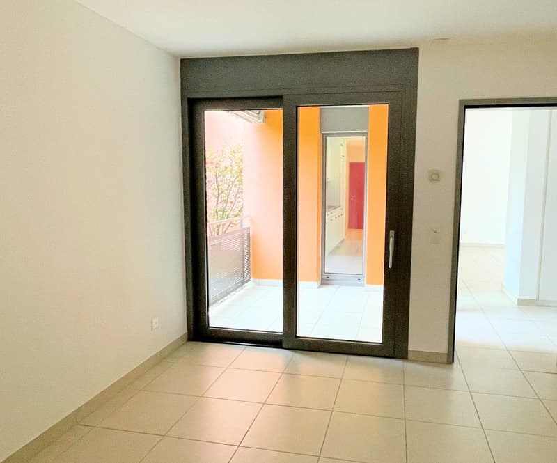 A sliding door leading to balcony, white tiles floor, a power outlet on the wall.