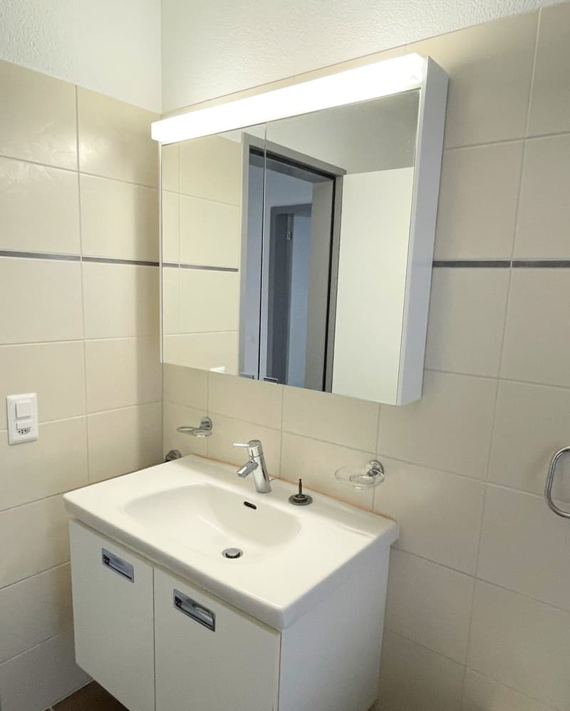 Bathroom: white walls, white sink, white mirror with lights, modern fixtures