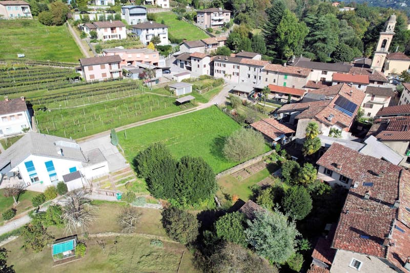 cluster of traditional stone buildings, red roofs, surrounding greenery, vineyards, narrow roads