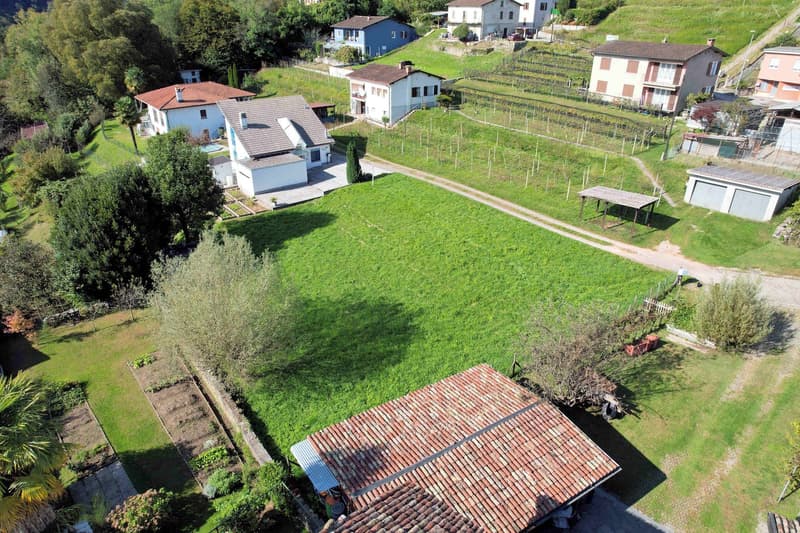 Multiple houses with gardens and farmland on a hillside